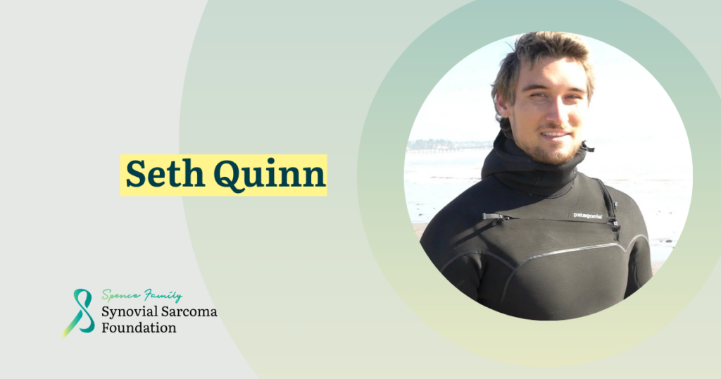 A man in a wetsuit stands on a beach, smiling at the camera. Text on the left reads "Seth Quinn" and "Synovial Sarcoma Foundation" with a ribbon logo. The background features soft green and cream tones.